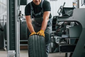 Front view. Man in uniform is working in the auto service photo