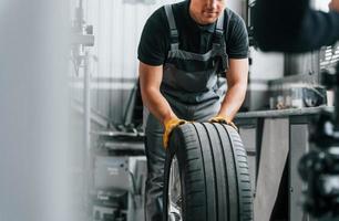 Close up view of wheel. Man in uniform is working in the auto service photo