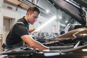 Ready to solve the problem. Man in uniform is working in the auto service photo