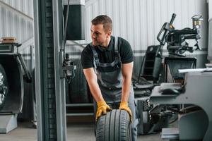 Front view. Man in uniform is working in the auto service photo