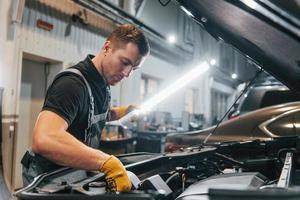 Ready to solve the problem. Man in uniform is working in the auto service photo