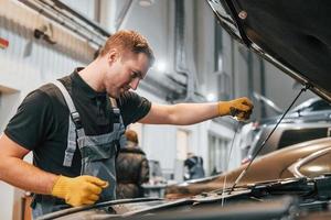 Ready to solve the problem. Man in uniform is working in the auto service photo