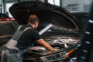Side view. Man in uniform is working in the auto service photo