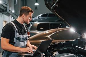 Side view. Man in uniform is working in the auto service photo
