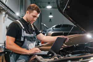 Side view. Man in uniform is working in the auto service photo