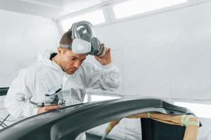 Working with car surface. Man in uniform is working in the auto service photo