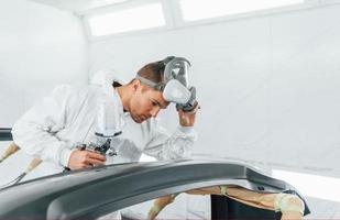 Working with car surface. Man in uniform is working in the auto service photo