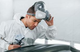 trabajando con la superficie del coche. el hombre de uniforme está trabajando en el servicio de automóviles foto