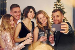 haciendo selfie grupo de personas tienen una fiesta de año nuevo en el interior juntos foto