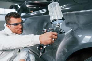 proceso de pintura del coche. el hombre de uniforme está trabajando en el servicio de automóviles foto