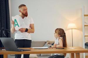 Little girl sitting by the table. Father with his little daughter is at home together photo