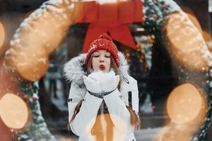 Playing with snow. Happy young woman standing outdoors and celebrating christmas holidays photo