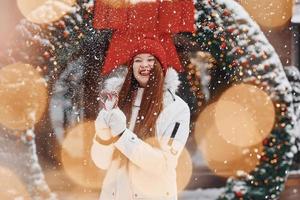 Holding sweets. Happy young woman standing outdoors and celebrating christmas holidays photo