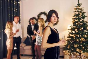 Woman standing in front of her friends. Group of people have a new year party indoors together photo