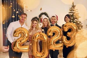 2023 is coming. Group of people have a new year party indoors together photo