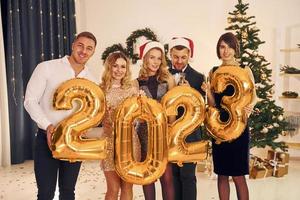 2023 is coming. Group of people have a new year party indoors together photo