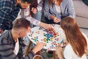 Focused at puzzle game. Group of friends have party indoors together photo