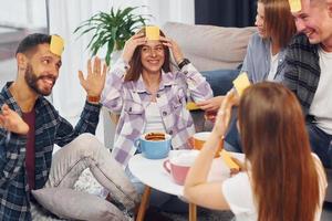 jugando quién soy yo juego. grupo de amigos tienen una fiesta en el interior juntos foto