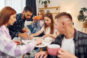 Focused at puzzle game. Group of friends have party indoors together photo