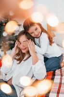 Mother with her little daughter is having fun indoors on the bed photo