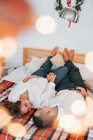 Laying down on the bed. Lovely couple celebrating holidays together indoors photo