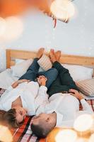 Laying down on the bed. Lovely couple celebrating holidays together indoors photo