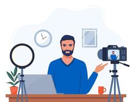 Man blogger records himself on video using a camera and a circle light lamp. Vector character influencer creating a video review for a blog. Vlogger records video indoors. Flat illustration.