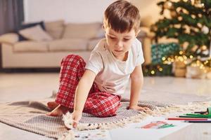 Little boy is in room with christmas tree is on the floor photo