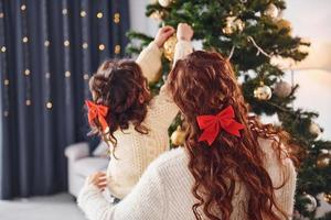 Decorating tree. Mother with her little daughter is at home photo