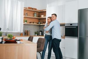 Dancing together. Couple preparing food at home on the modern kitchen photo