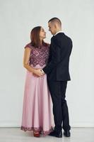 pareja en ropa formal de pie en el estudio con fondo blanco foto