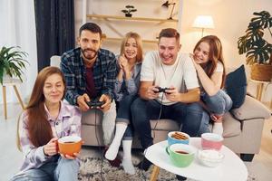 Using joysticks to play video game. Group of friends have party indoors together photo