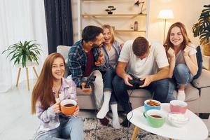 Using joysticks to play video game. Group of friends have party indoors together photo