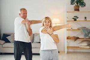 haciendo estiramientos. el hombre y la mujer mayores están juntos en casa foto