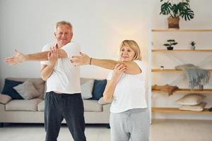 Doing stretching. Senior man and woman is together at home photo