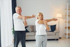 Sportive exercises. Senior man and woman is together at home photo