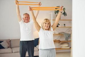 haciendo estiramientos y ejercicios de fitness. el hombre y la mujer mayores están juntos en casa foto