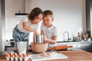 trabajando con masa. niño y niña preparando galletas navideñas en la cocina foto