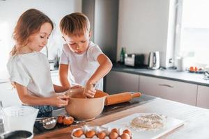 Preparing food together. Little boy and girl on the kitchen photo