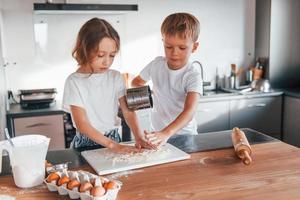 Weekend activities. Little boy and girl preparing Christmas cookies on the kitchen photo