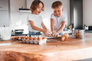 Cheerful emotions. Little boy and girl preparing Christmas cookies on the kitchen photo