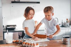 Two people together. Little boy and girl preparing Christmas cookies on the kitchen photo