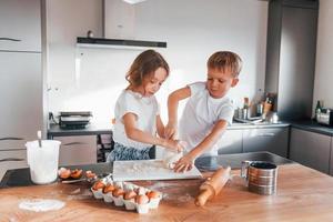 Cheerful emotions. Little boy and girl preparing Christmas cookies on the kitchen photo
