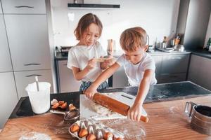 dos personas juntas. niño y niña preparando galletas navideñas en la cocina foto