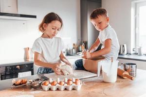 Making sweets. Little boy and girl preparing Christmas cookies on the kitchen photo