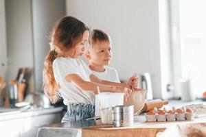 Learning how to cook. Little boy and girl preparing Christmas cookies on the kitchen photo