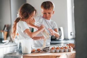 aprendiendo a cocinar. niño y niña preparando galletas navideñas en la cocina foto