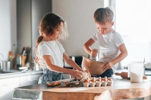sentado en la mesa. niño y niña preparando galletas navideñas en la cocina foto