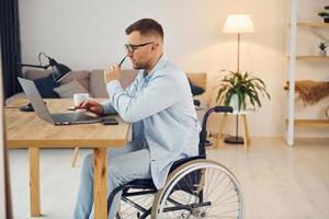 Smart freelance worker. Disabled man in wheelchair is at home photo