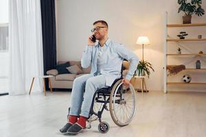 Using phone. Disabled man in wheelchair is at home photo